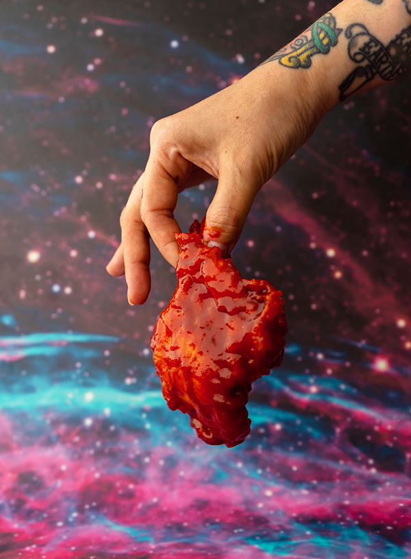 Koreaans gefrituurde kip vastgehouden aan twee vingers voor een space backdrop.